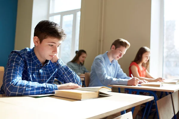 Grupp elever med böcker skriver skolan test — Stockfoto