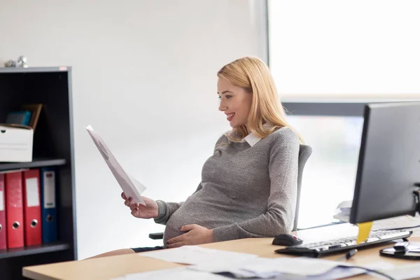 Femme d'affaires enceinte lecture de documents au bureau — Photo