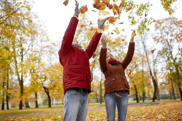 Glückliches junges Paar wirft Herbstblätter in Park — Stockfoto