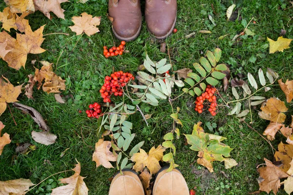 Piedi in stivali con rowanberries e foglie autunnali — Foto Stock