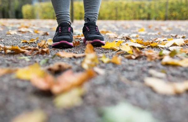 Close up of young woman running in autumn park — Stock Photo, Image