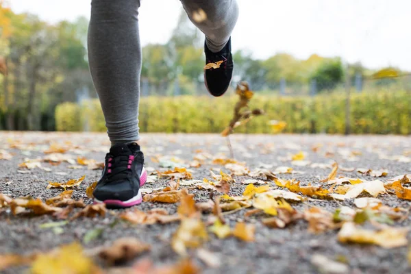 Nahaufnahme einer jungen Frau, die im Herbstpark läuft — Stockfoto