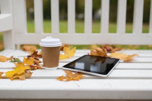 Tablette pc et tasse de café sur banc dans le parc d'automne — Photo