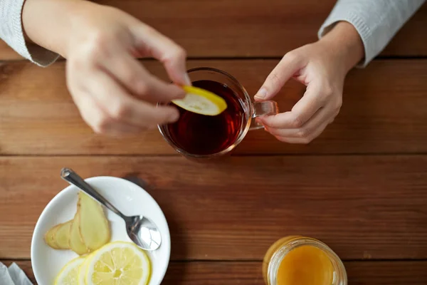 Primer plano de la mujer añadiendo limón a la taza de té — Foto de Stock