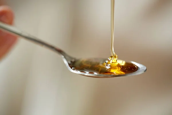 Nahaufnahme von Honig, der in Teelöffel gegossen wird — Stockfoto