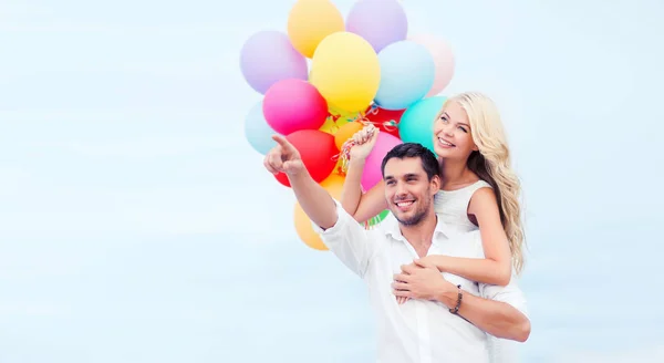 Casal com balões coloridos no lado do mar — Fotografia de Stock