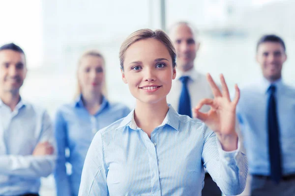 Smiling businesswoman showing ok sign in office — Stock Photo, Image