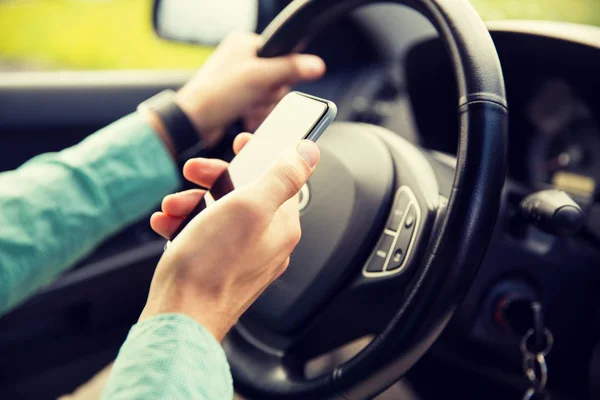 Close up of man hand with smartphone driving car — Stock Photo, Image