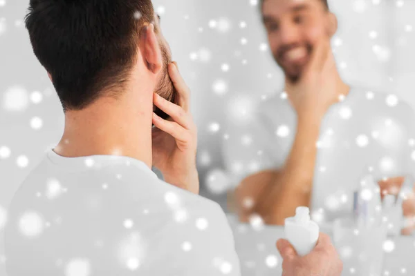 Close up de homem aplicando creme no rosto no banheiro — Fotografia de Stock