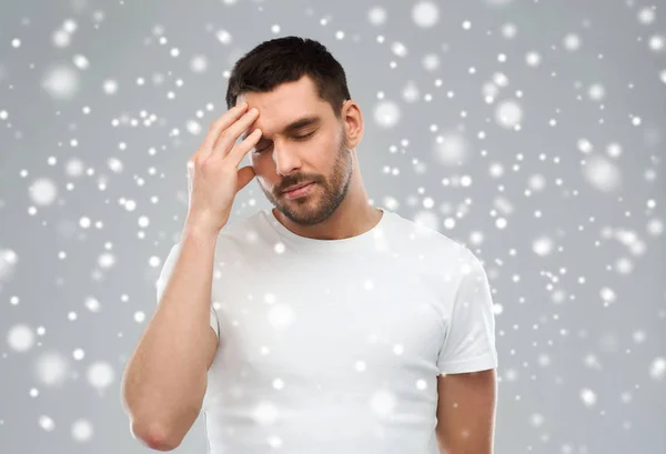 Young man suffering from headache over snow — Stock Photo, Image