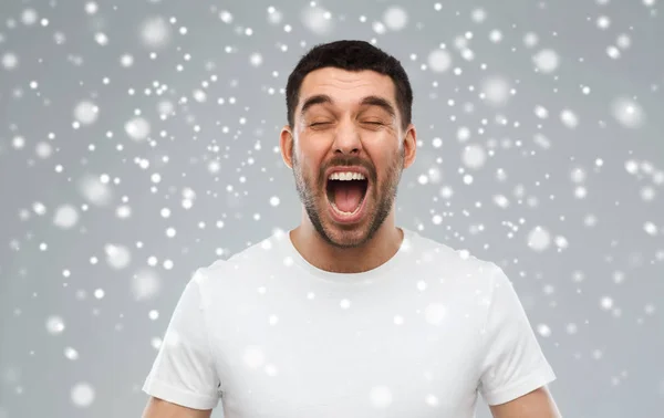 Louco gritando homem em t-shirt sobre neve fundo — Fotografia de Stock