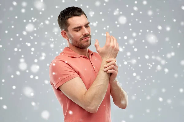 Hombre infeliz que sufre de dolor en la mano sobre la nieve — Foto de Stock