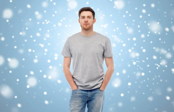 Jovem em camiseta cinza e jeans sobre a neve — Fotografia de Stock