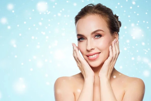 Beautiful young woman touching her face over snow — Stock Photo, Image