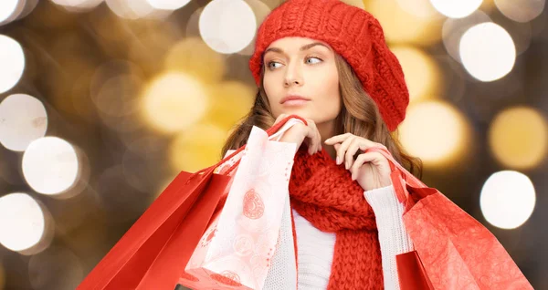 Mulher de chapéu vermelho e cachecol segurando sacos de compras — Fotografia de Stock