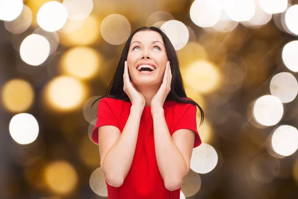 Mujer riendo asombrada en vestido rojo mirando hacia arriba — Foto de Stock