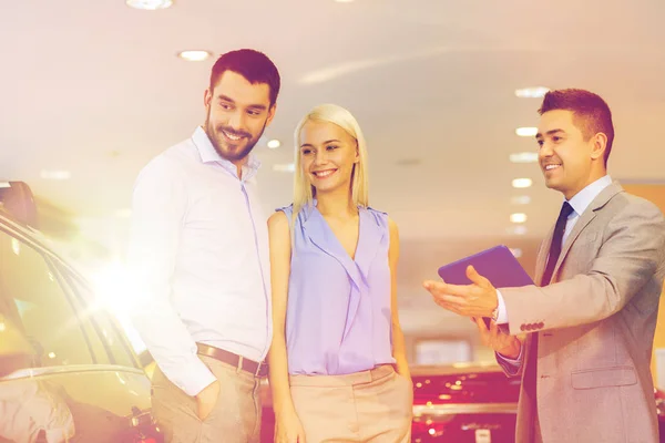 Feliz pareja con concesionario de coches en auto show o salón —  Fotos de Stock