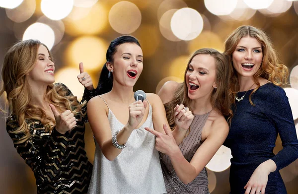 Jovens mulheres felizes com microfone cantando karaoke — Fotografia de Stock