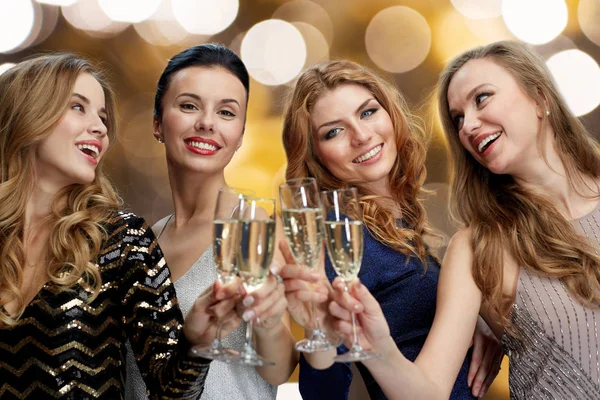 Mulheres felizes batendo taças de champanhe sobre luzes — Fotografia de Stock