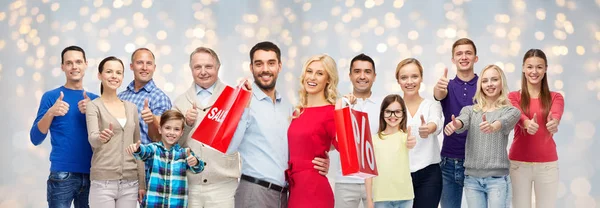 Gente feliz con bolsas de compras mostrando los pulgares hacia arriba — Foto de Stock