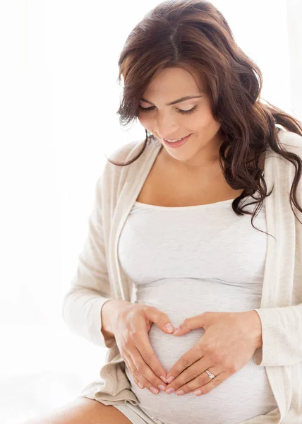 Gelukkig zwangere vrouw hart gebaar thuis — Stockfoto