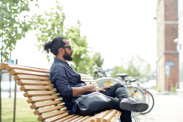 Człowiek z plecaka, siedząc na ławce ulicy miasta — Zdjęcie stockowe