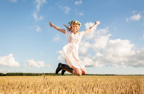 Счастливая женщина в венке прыгает на зерновом поле — стоковое фото