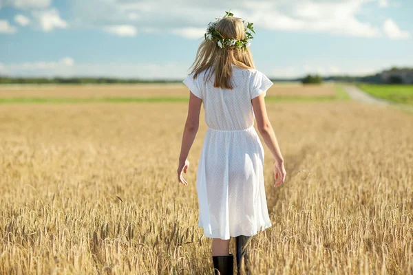 Glückliche junge Frau im Blumenkranz auf einem Getreidefeld — Stockfoto
