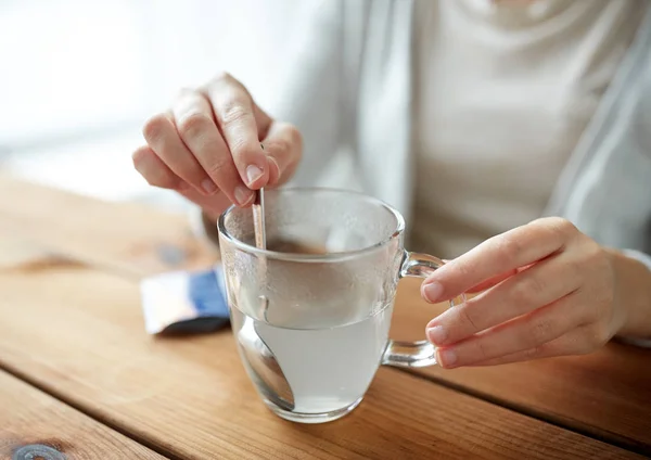 Vrouw medicatie roeren in kopje water — Stockfoto