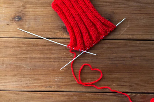 Knitting needles and thread in heart shape on wood — Stock Photo, Image
