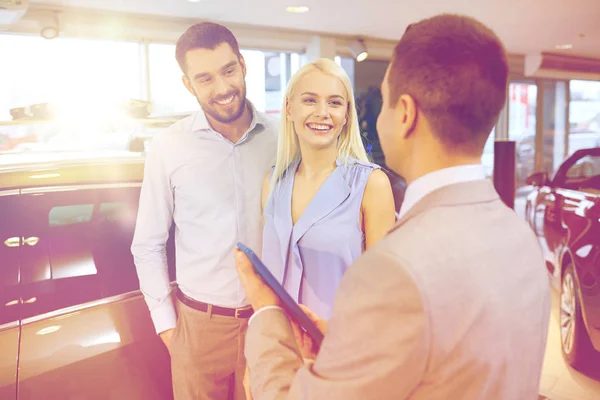 Happy couple with car dealer in auto show or salon — Stock Photo, Image