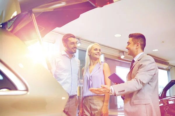 Happy couple with car dealer in auto show or salon — Stock Photo, Image