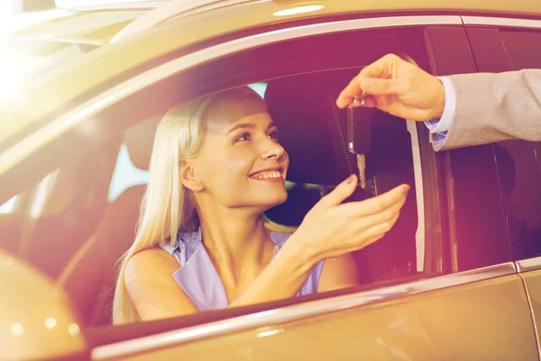 Mulher feliz recebendo chave do carro em auto show ou salão — Fotografia de Stock