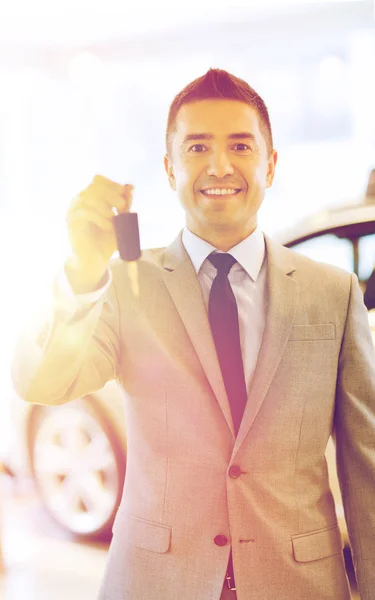 Hombre feliz que muestra la llave en el salón auto del espectáculo o del coche —  Fotos de Stock