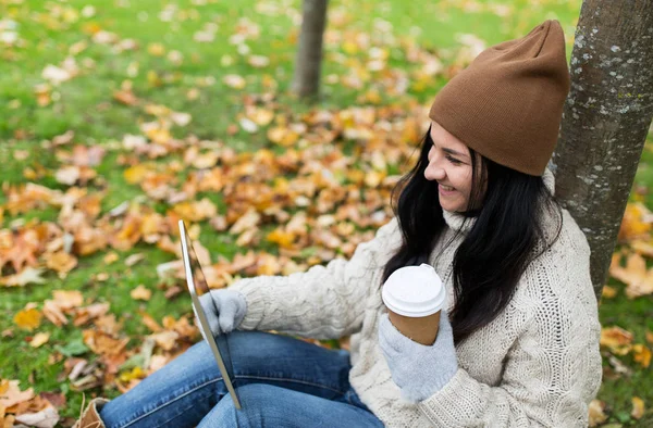 Kobieta z komputera typu tablet i kawa w jesienny park — Zdjęcie stockowe