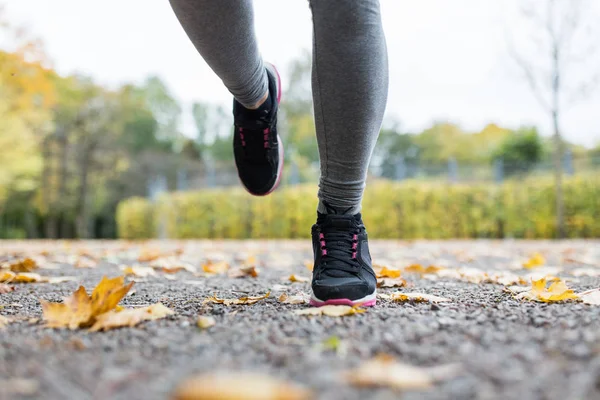 Close up of young woman running in autumn park — Stock Photo, Image
