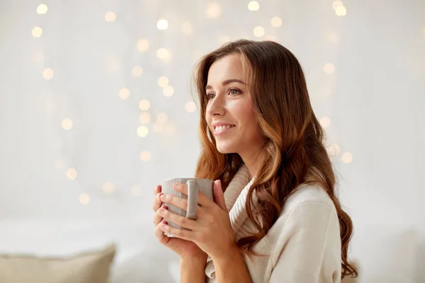 Счастливая женщина с чашкой чая или кофе дома — стоковое фото