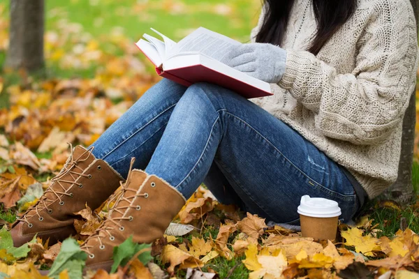 Frau mit Buch trinkt Kaffee im Herbstpark — Stockfoto
