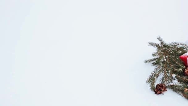 Caja de regalo y corona de abeto con conos en la nieve — Vídeo de stock