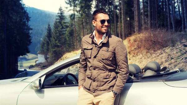 Щасливий чоловік біля кабріолетного автомобіля над природою — стокове фото