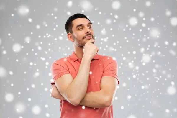 Homem em polo t-shirt pensando sobre fundo de neve — Fotografia de Stock