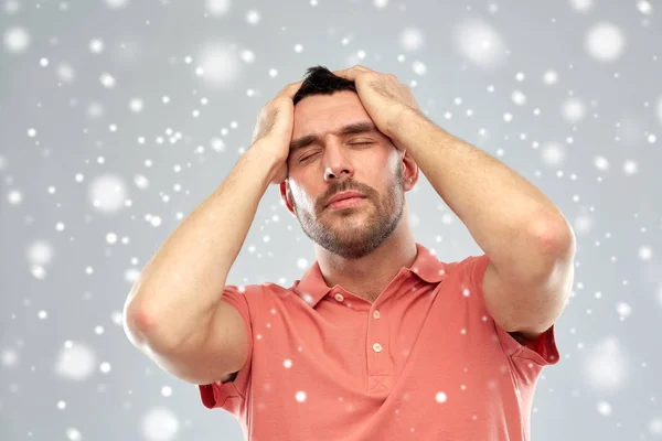 Homem infeliz que sofre de dor de cabeça sobre a neve — Fotografia de Stock