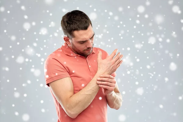 Hombre infeliz que sufre de dolor en la mano sobre la nieve — Foto de Stock