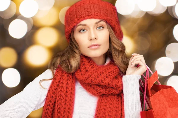 Donna in cappello rosso e sciarpa che tiene borse della spesa — Foto Stock