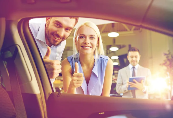 Casal feliz com revendedor de carro em auto show ou salão — Fotografia de Stock