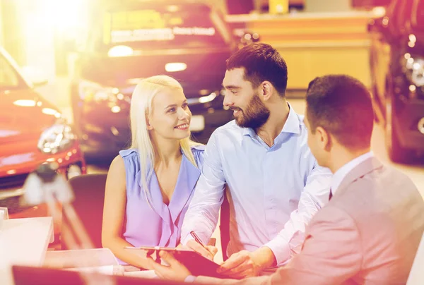 Glückliches Paar mit Autohändler in Auto-Show oder Salon — Stockfoto