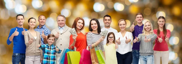 Glada människor med shoppingväskor och pengar — Stockfoto