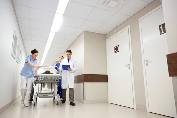 Médicos e paciente em maca hospitalar na emergência — Fotografia de Stock