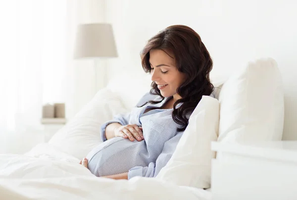 Ευτυχισμένη έγκυος γυναίκα ξαπλωμένος στο κρεβάτι στο σπίτι — Φωτογραφία Αρχείου