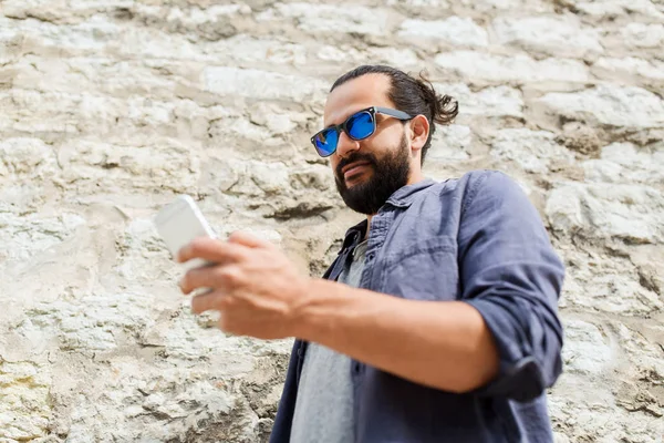 Hombre mensaje de texto en el teléfono inteligente en la pared de piedra — Foto de Stock